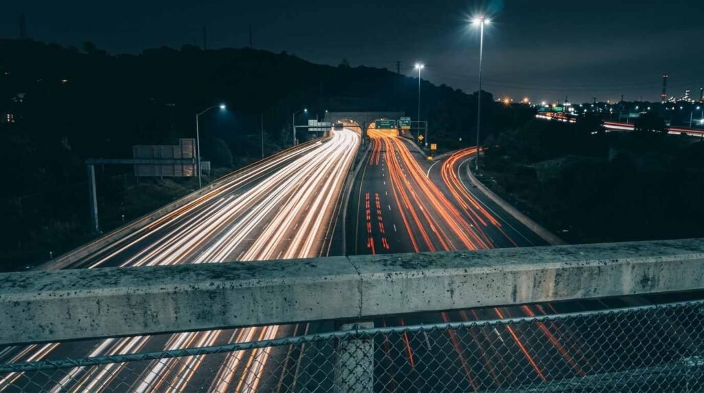 Light trails on a highway converging into a tunnel entrance, a few tail lights standing apart.