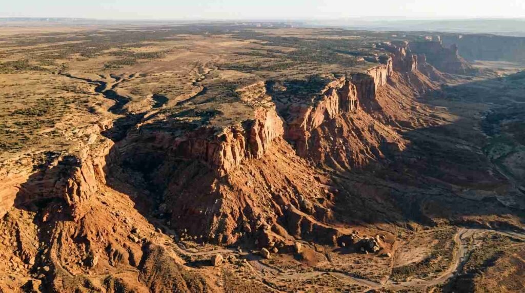 Eroded red cliff escarpment above a dry plateau from the air